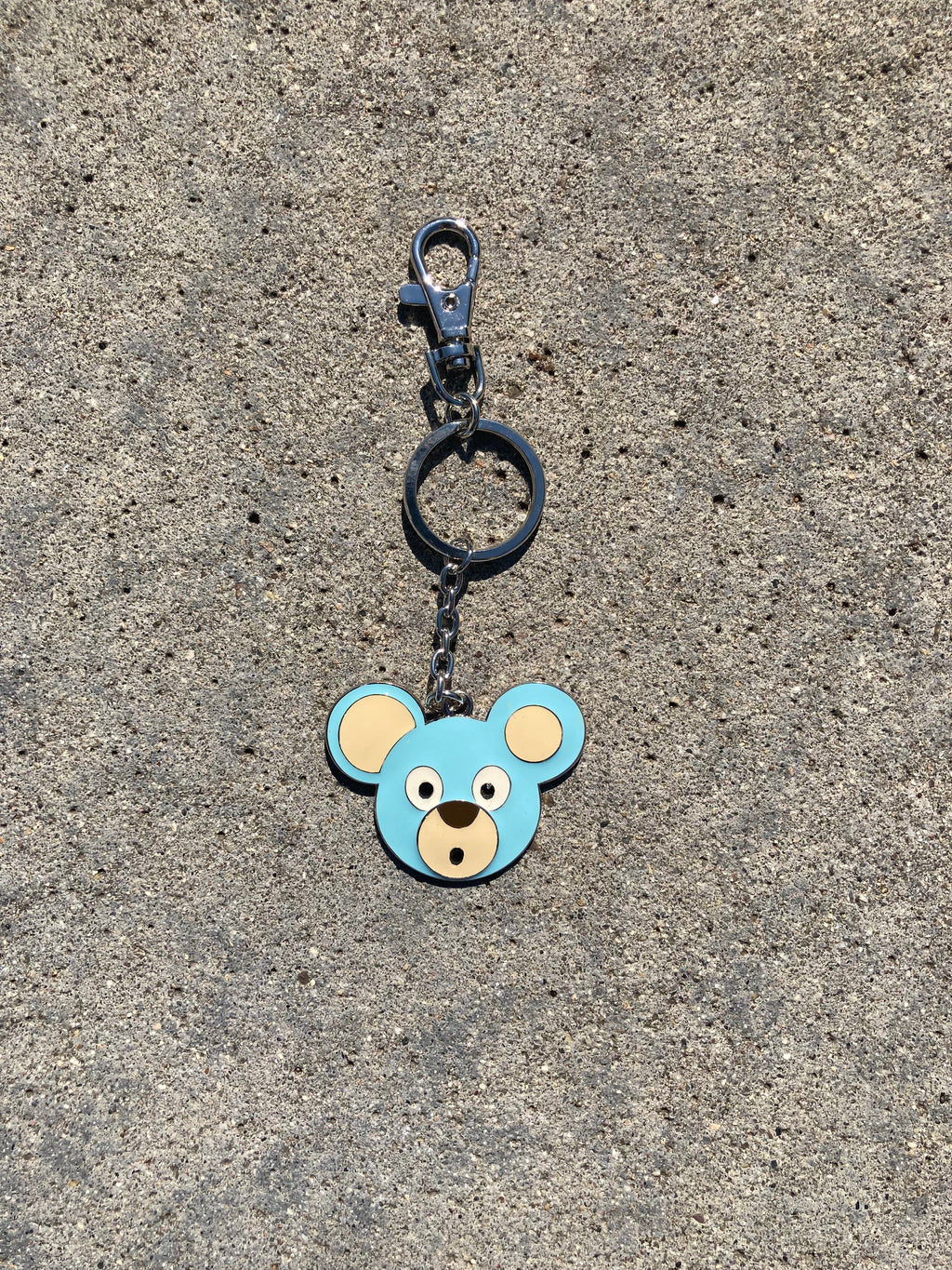 O. Bear keychain with a bear face design on a concrete surface