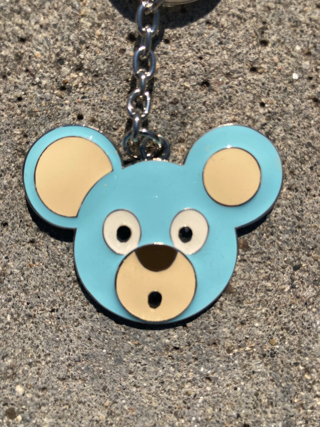 O. Bear Blue bear-shaped keychain on a concrete surface