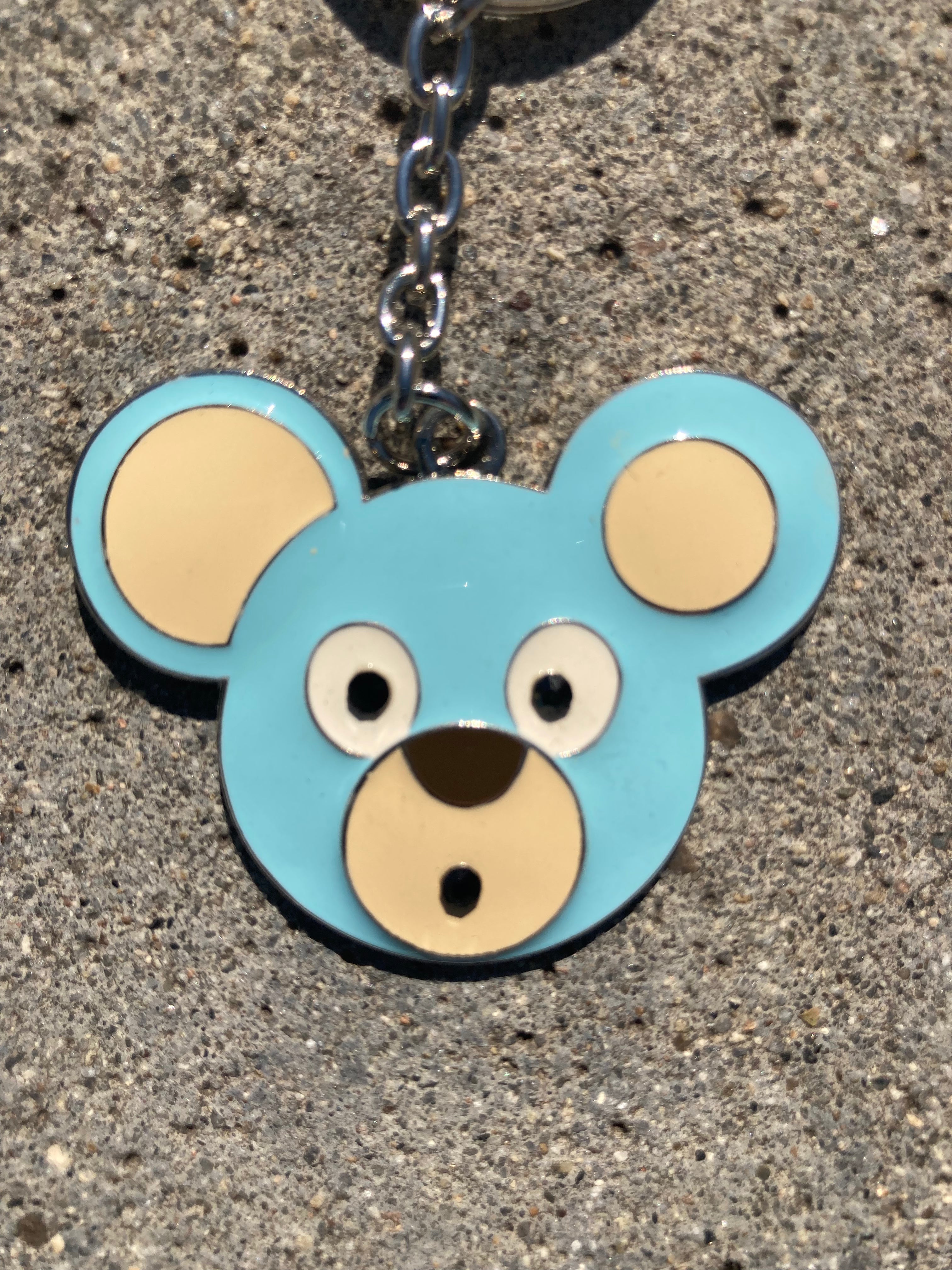 O. Bear Blue bear-shaped keychain on a concrete surface