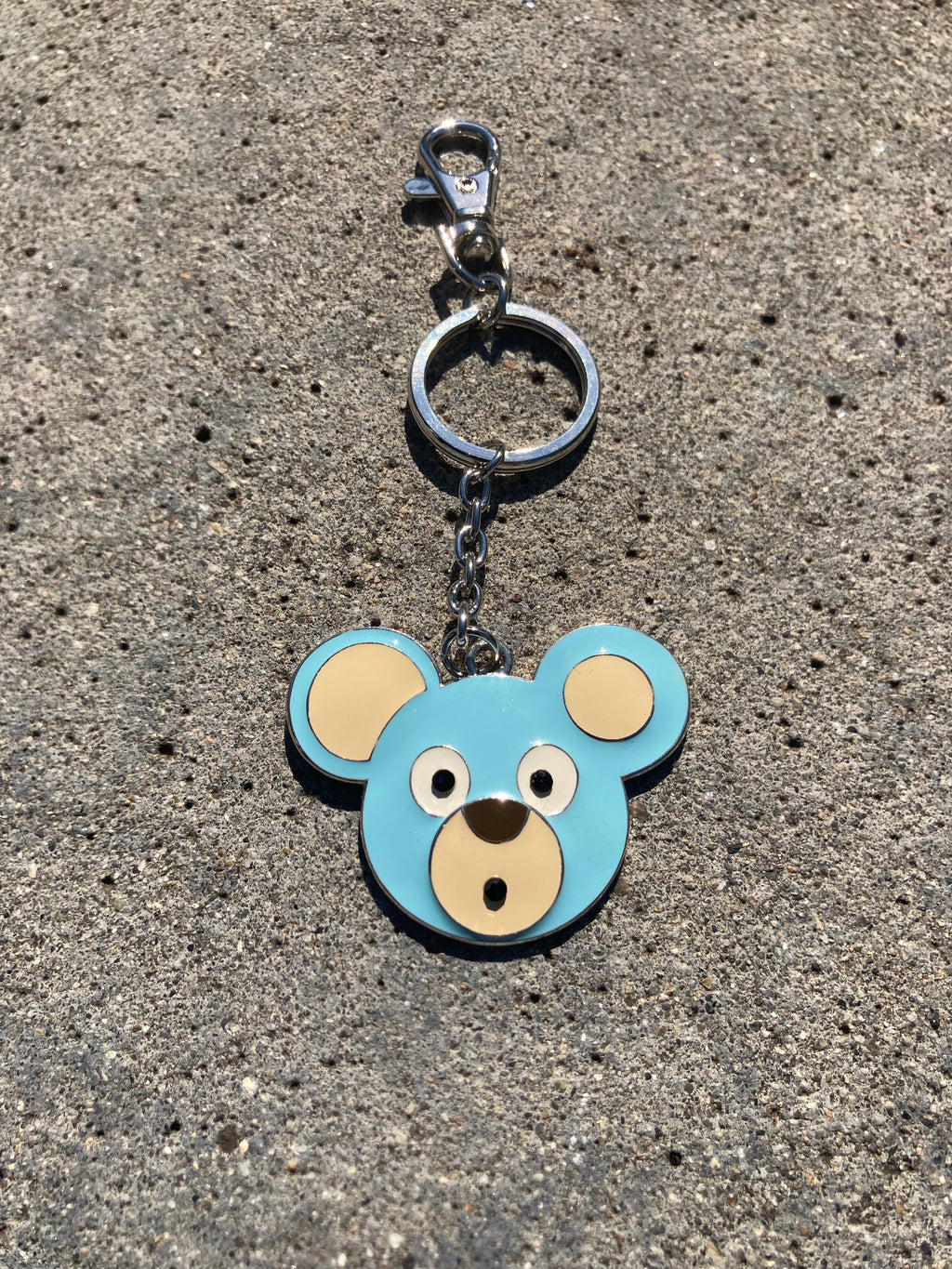 O. Bear keychain with bear face design on a textured surface