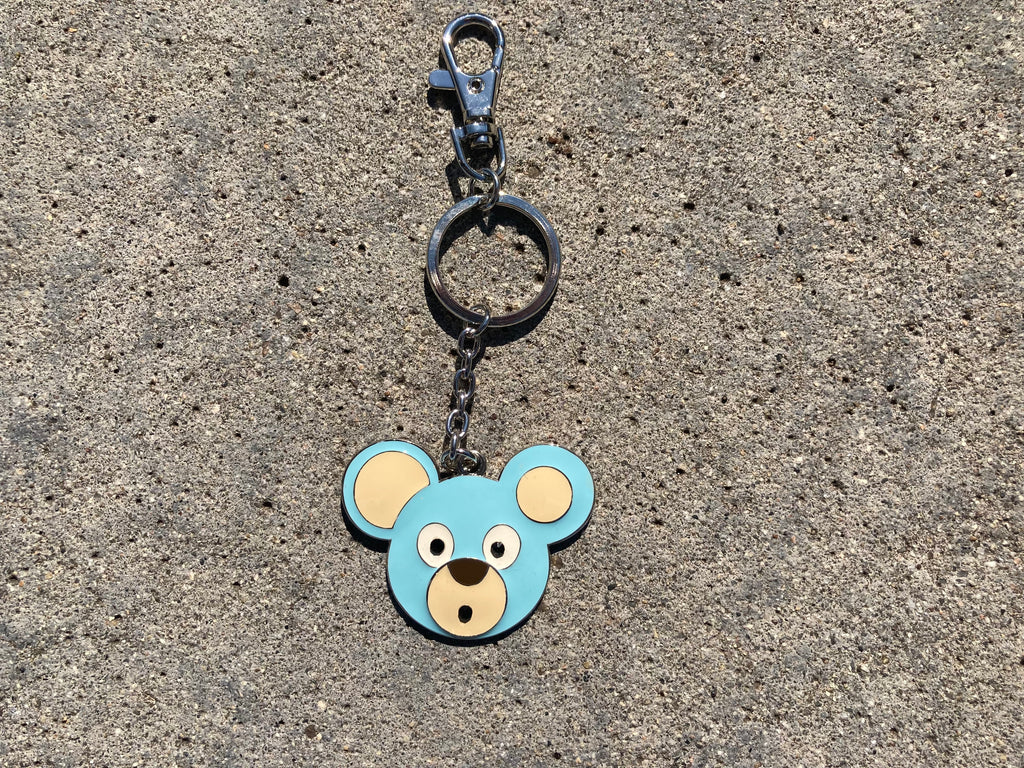 O. Bear Blue bear-shaped keychain on a concrete surface