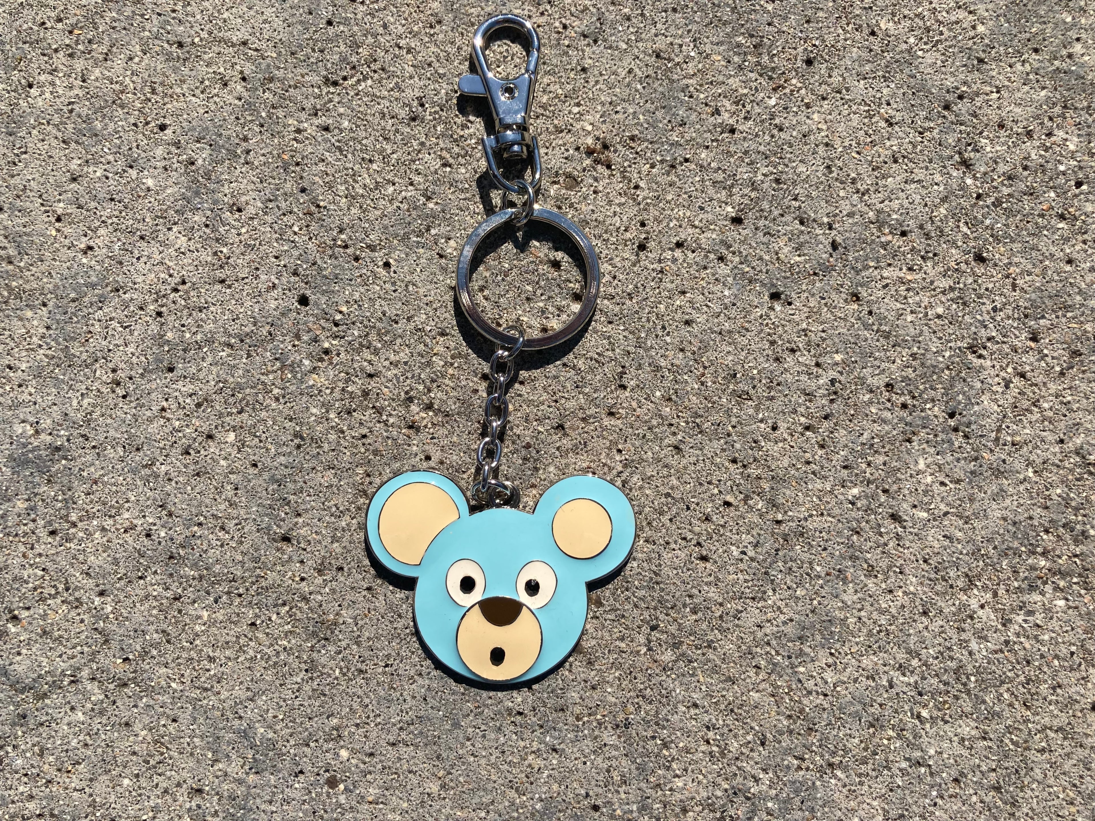 O. Bear Blue bear-shaped keychain on a concrete surface