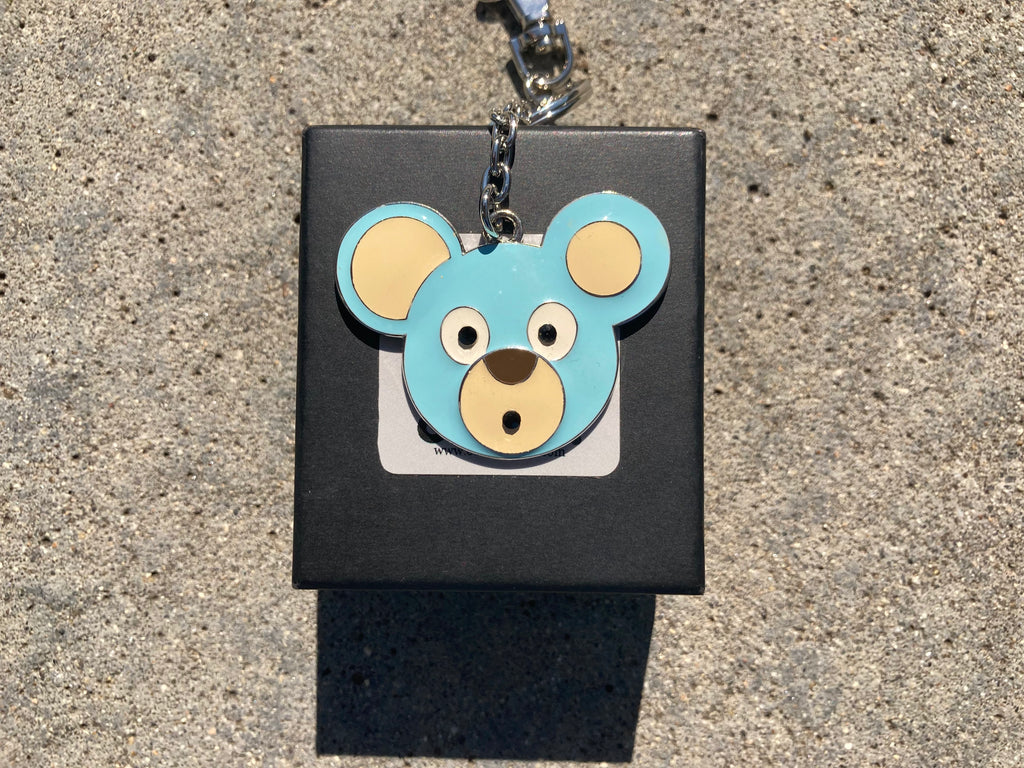 O. Bear blue bear-shaped keychain on a black card with a gray background
