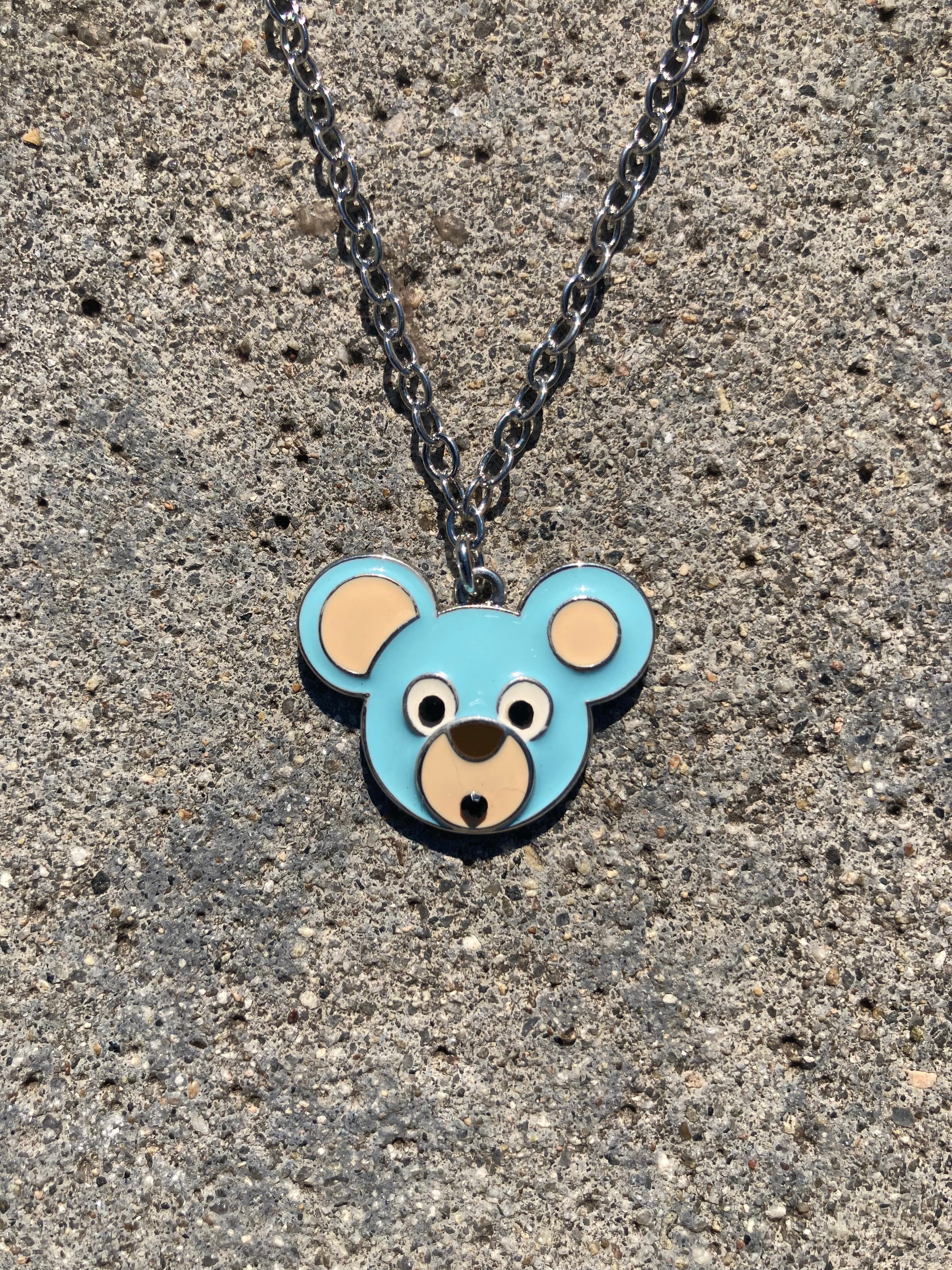 Necklace with a bear-shaped pendant on a concrete surface