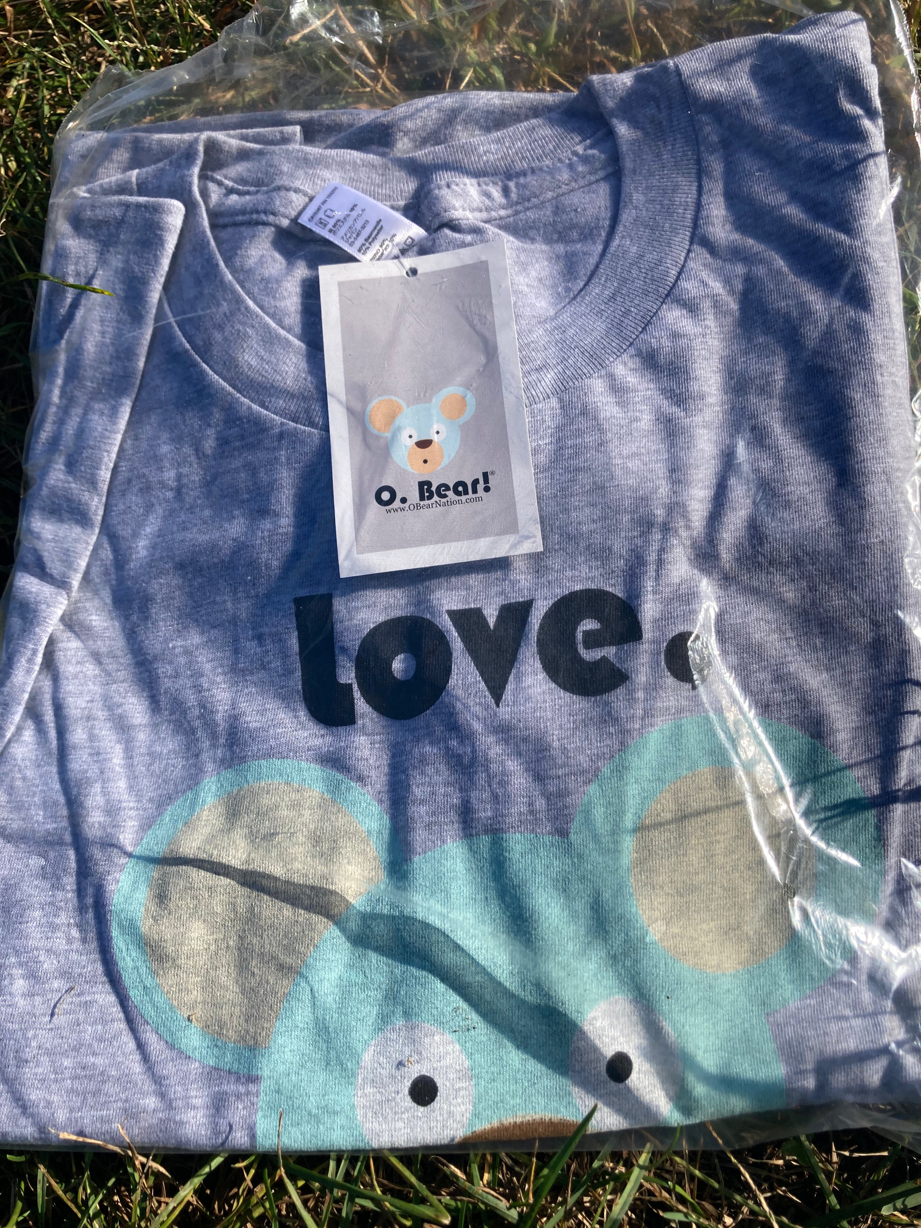 Gray t-shirt with 'Love, O. Bear!' and bear design, on grass