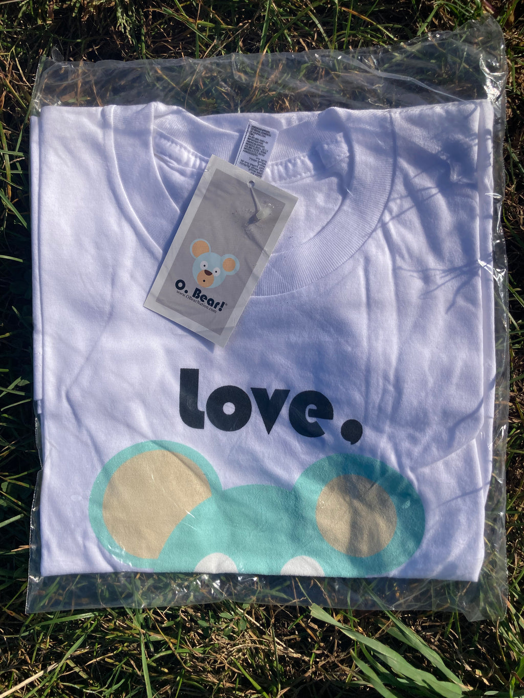 White t-shirt with 'Love, O. Bear' and bear design on grass