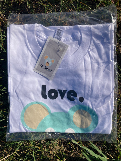White t-shirt with 'Love, O. Bear' and bear design on grass