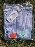 Folded grey t-shirt with a bear design and 'I love heart OBear O. Bear' text, still in packaging on grass.