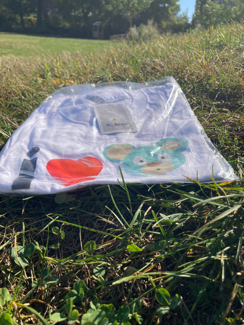 Packaged O. Bear t-shirt with cartoon designs on grass